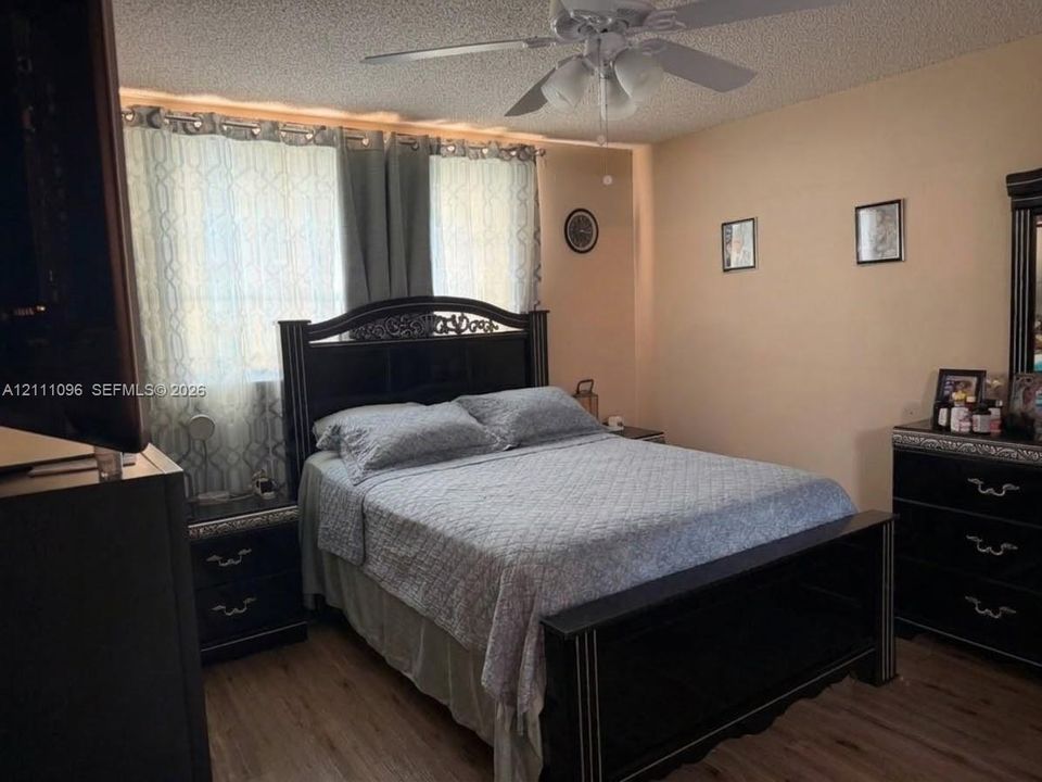 Wood-finish flooring, textured ceiling, and a ceiling-mounted light fixture with a central fan