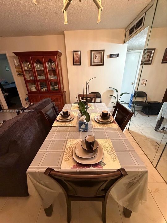 Dining area featuring large-format tile flooring, full-wall mirror paneling, and an integrated ceiling-mounted light fixture