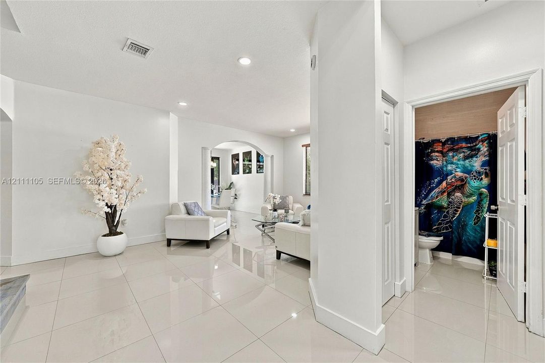 Interior featuring large-format tile flooring, recessed lighting, and an arched architectural opening