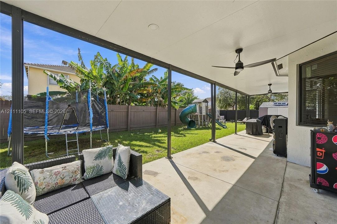 Covered concrete patio featuring ceiling fans and a fenced backyard
