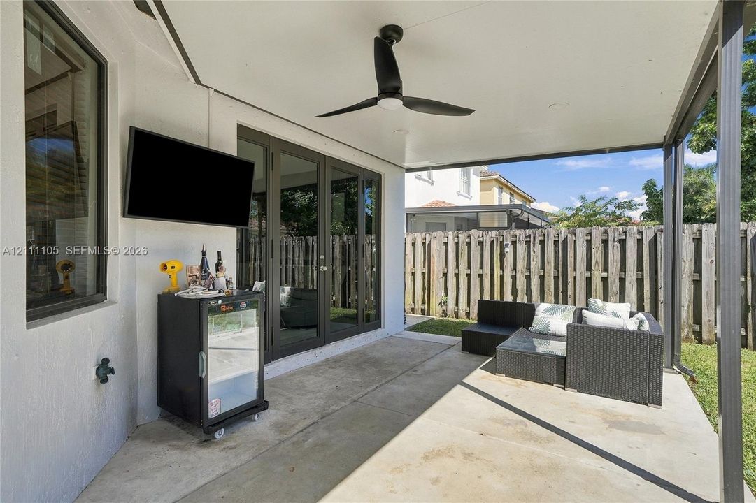 Covered patio featuring concrete flooring, a ceiling fan, and multi-panel glass doors