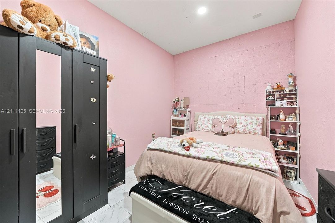 Interior room featuring masonry block wall construction and white stone-finish flooring