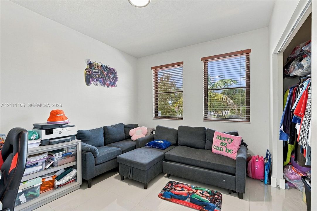 Neutral wall finishes, polished tile flooring, two windows with horizontal blinds, and a built-in closet with sliding doors