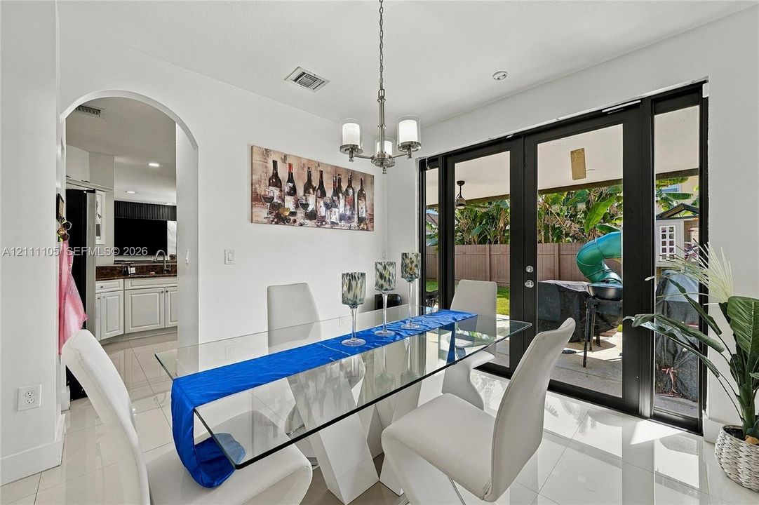 Dining area featuring polished tile flooring, architectural arched entryway, and multi-panel black-framed glass exterior doors