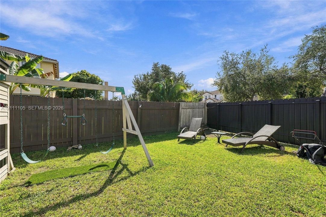 Fenced backyard featuring a manicured lawn and mature trees