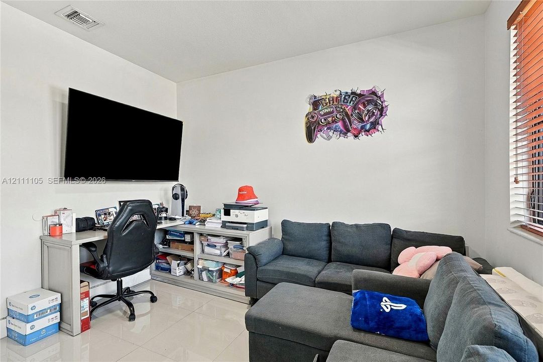 Interior space featuring large-format tile flooring and wood-slat window blinds