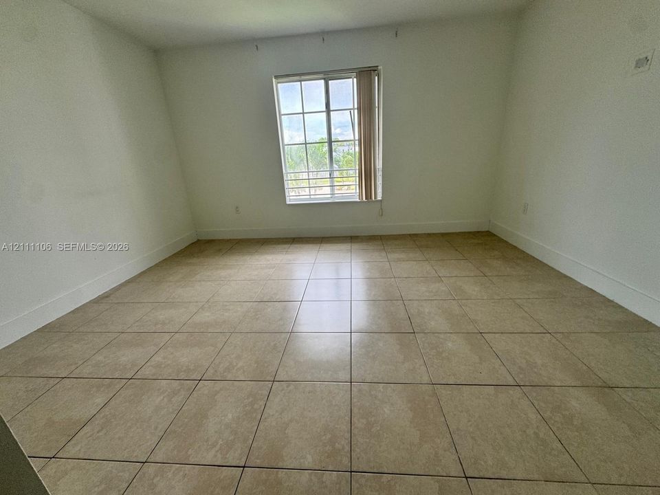 Neutral interior space featuring large-format tile flooring and a multi-pane window
