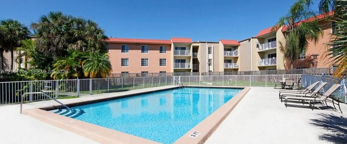 Rectangular swimming pool featuring a concrete deck and metal perimeter fencing