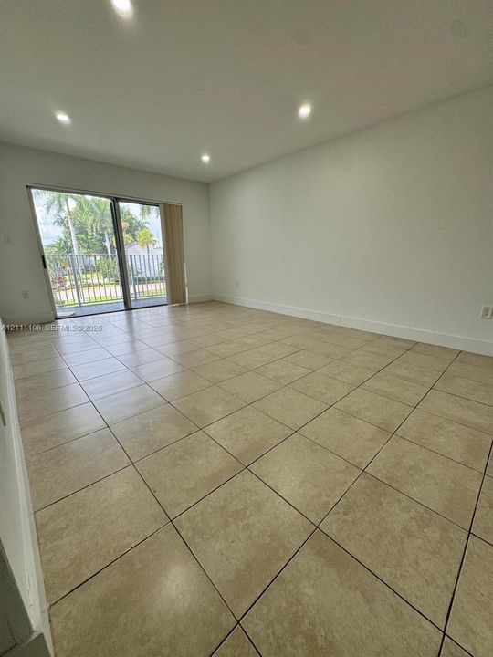 Neutral-toned tile flooring, recessed ceiling lighting, and sliding glass door with external balcony access