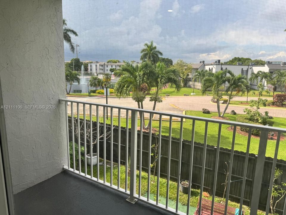 Covered balcony featuring white metal railings, a screened enclosure, and concrete flooring