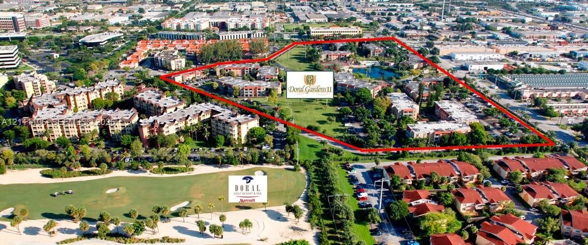 Aerial perspective of a multi-building residential complex featuring extensive green space, a central water feature, multiple parking areas, and mature landscaping