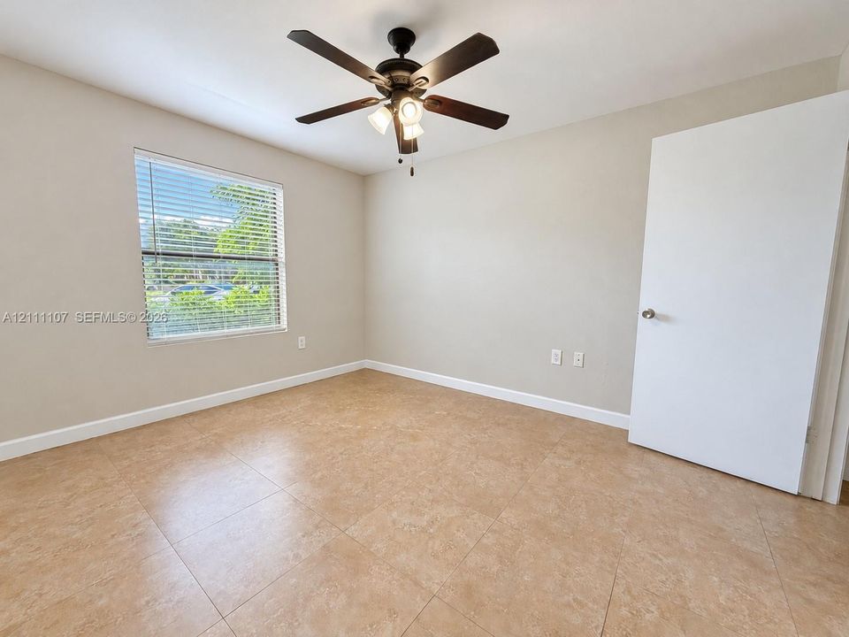Room featuring large-format neutral tile flooring, multi-blade ceiling fan with integrated lighting, and a single-hung window with horizontal blinds