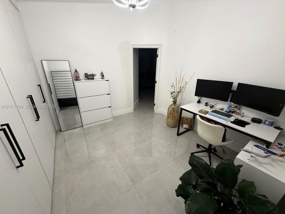 Large-format polished tile flooring, full-height white cabinetry with matte black hardware, and contemporary multi-arm ceiling fixture