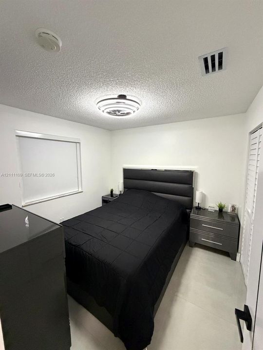Neutral-toned interior featuring tiled flooring, a modern flush-mount circular lighting fixture, and a louvered closet door