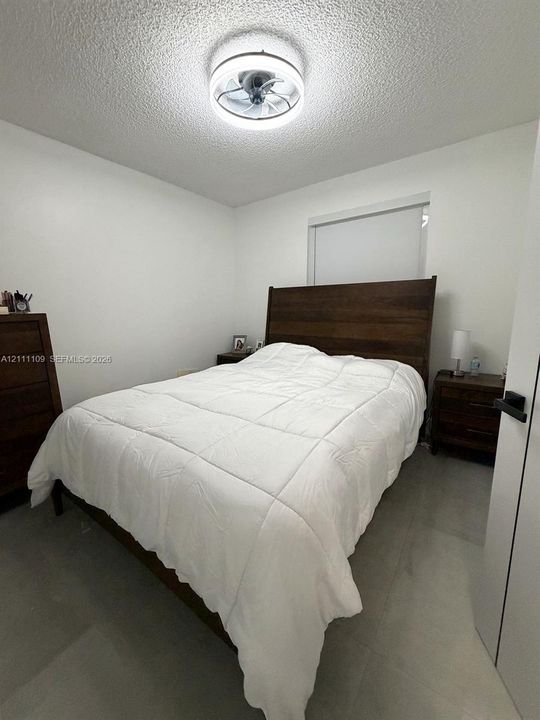 Bedroom featuring light-toned tile flooring, recessed window, and contemporary circular LED ceiling light fixture