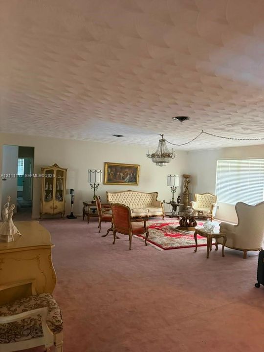 Textured ceiling, crystal-style chandelier, and horizontal window blinds
