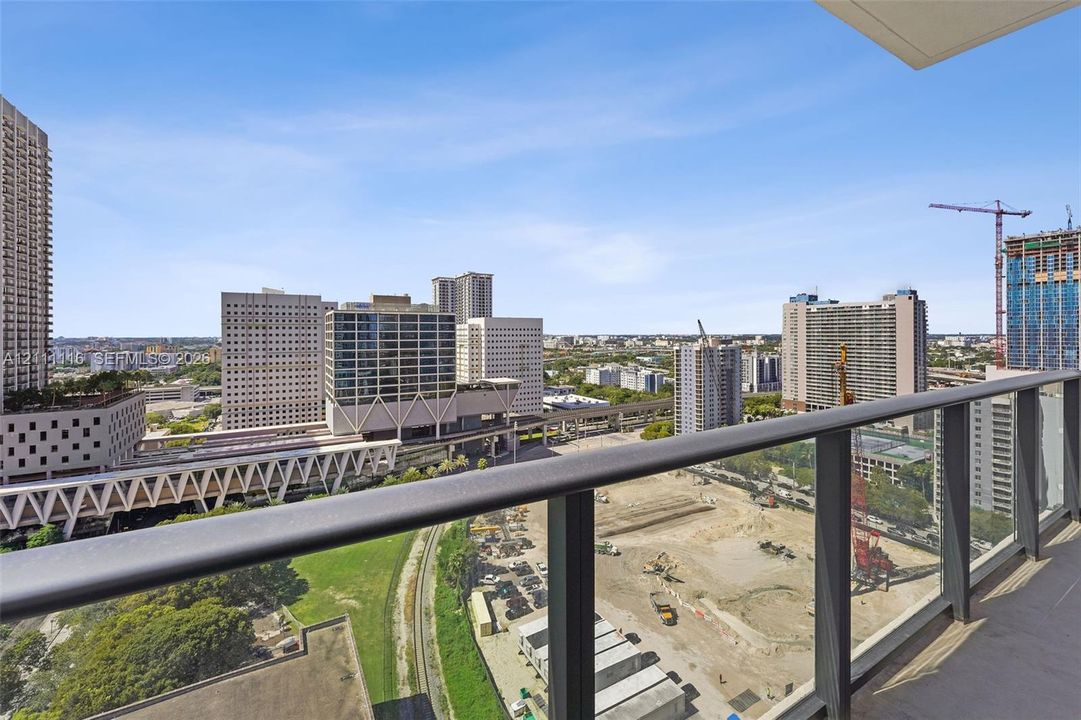 Private balcony with dark metal railings and concrete flooring, featuring an expansive skyline cityscape