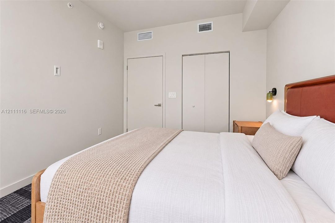 Neutral-toned interior featuring patterned carpeting, matte-finish walls, and dual closet access with solid-core swing and bi-fold doors