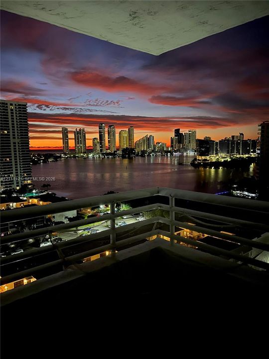 Private balcony featuring a metal railing and a backdrop of waterfront skyline scenery