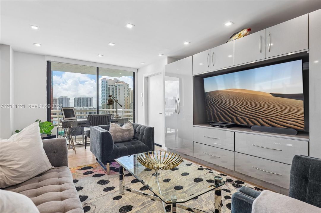 Built-in high-gloss cabinetry with integrated shelving and storage, floor-to-ceiling glass sliding doors, recessed lighting, and wood-finish flooring