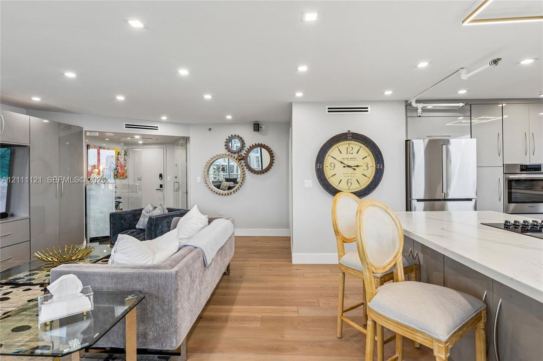 Open-concept interior featuring light wood-finish flooring, recessed lighting, and a kitchen island with a white countertop