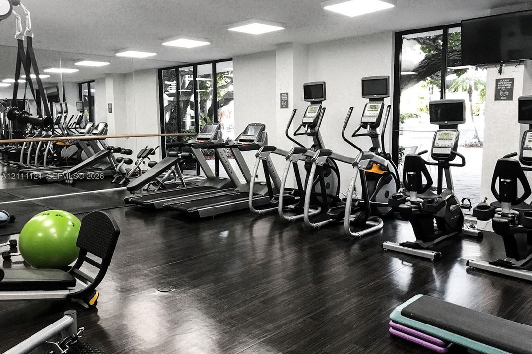 Fitness center featuring dark wood-finish flooring, floor-to-ceiling windows, and recessed square lighting
