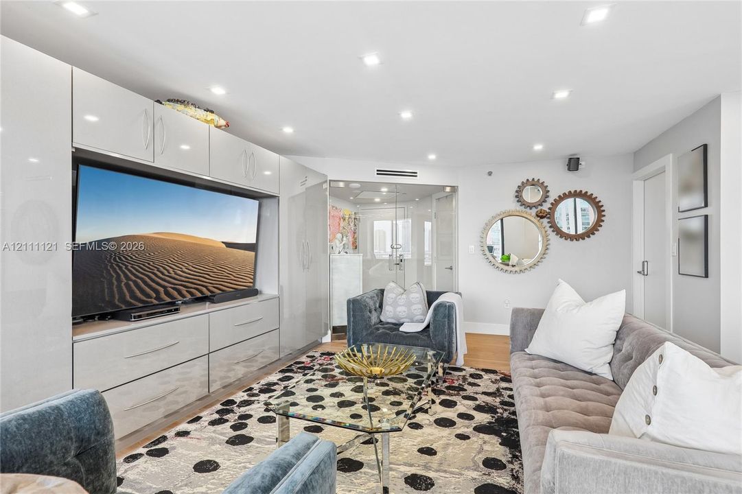 Built-in high-gloss cabinetry, recessed ceiling lighting, and glass-enclosed entry