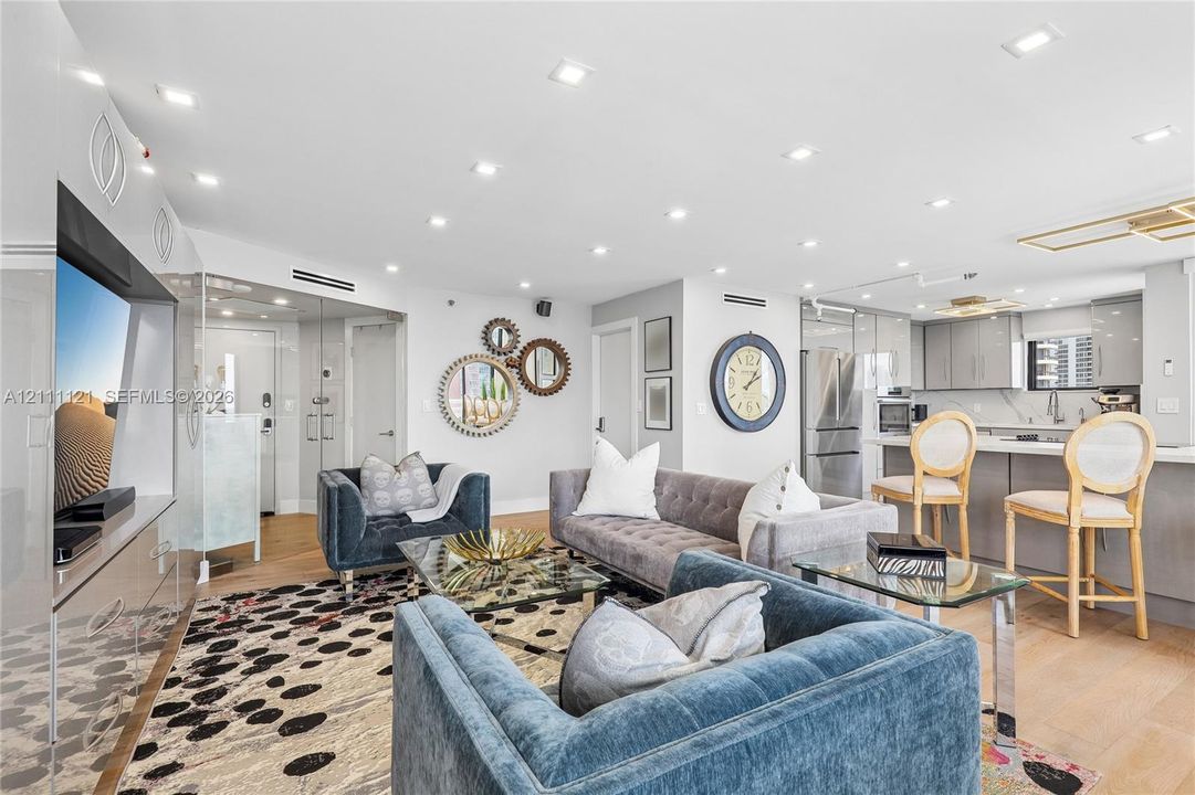 Open-concept interior featuring light wood-finish flooring, recessed lighting, integrated cabinetry, and a kitchen island with stone countertops