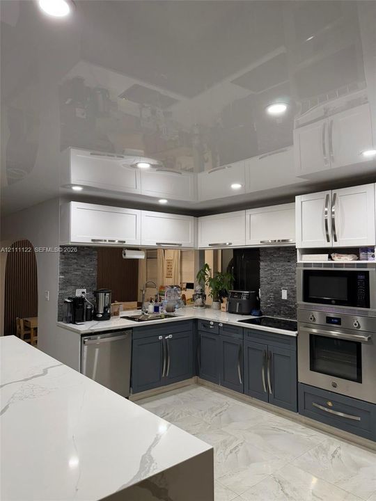 Kitchen featuring two-tone cabinetry, high-gloss ceiling finish, stone-surfaced countertops, stone-tile backsplash, and recessed lighting