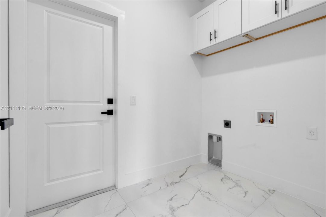Laundry room with washer/dryer hookups and overhead cabinet storage.
