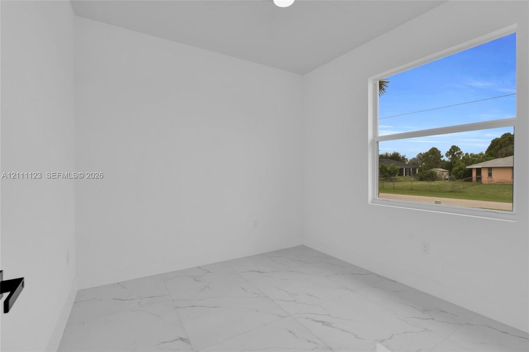 Bedroom with large window and porcelain tile flooring.