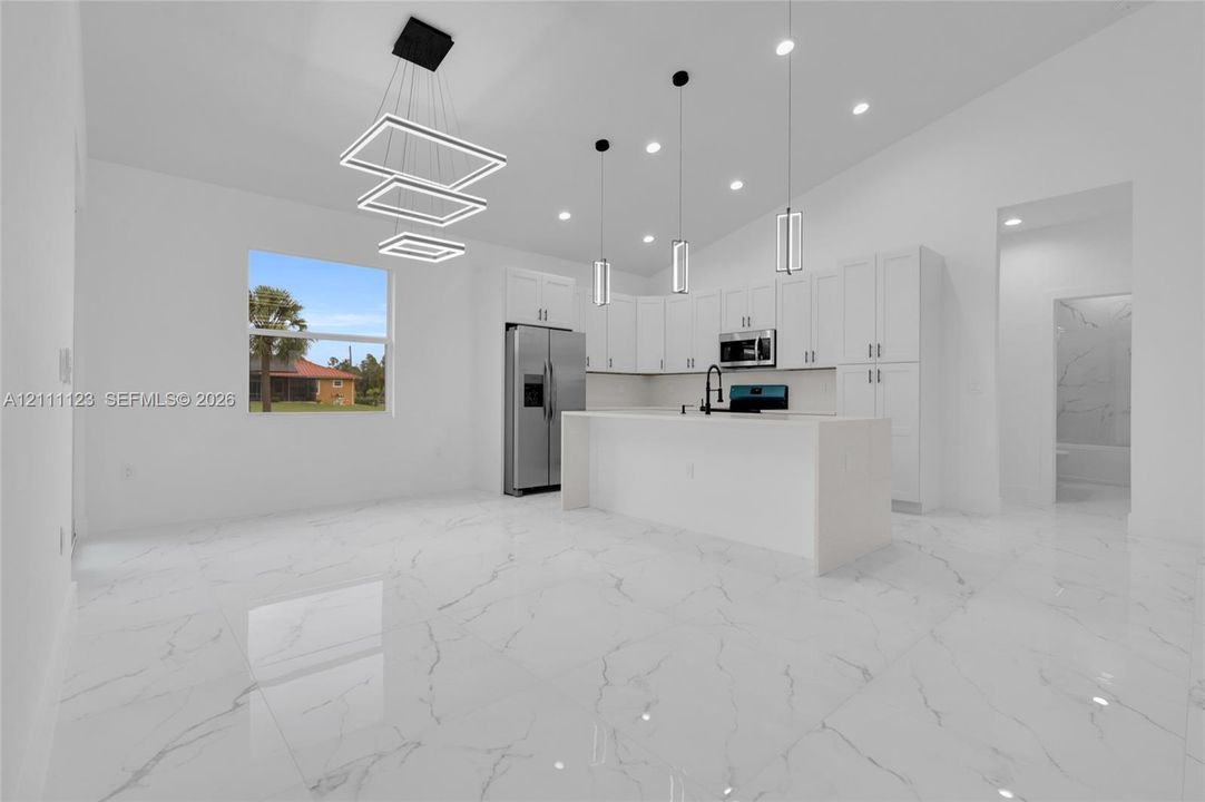 Dining area with modern light fixture, open to the kitchen island.