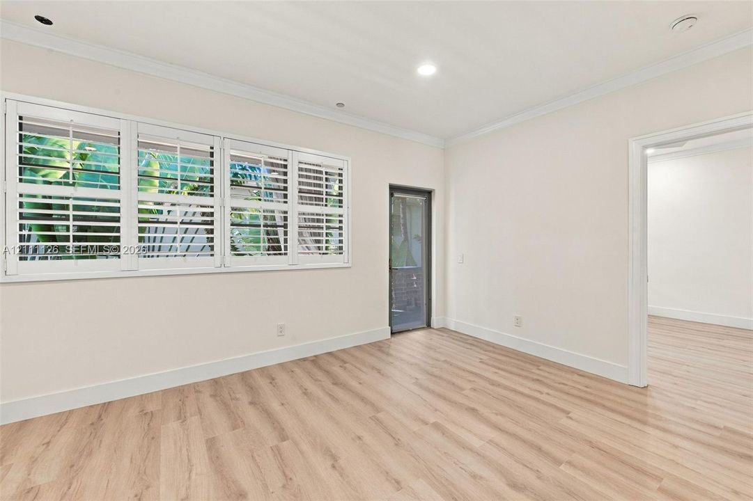 Interior space featuring light wood-finish flooring, plantation shutters, recessed lighting, and crown molding