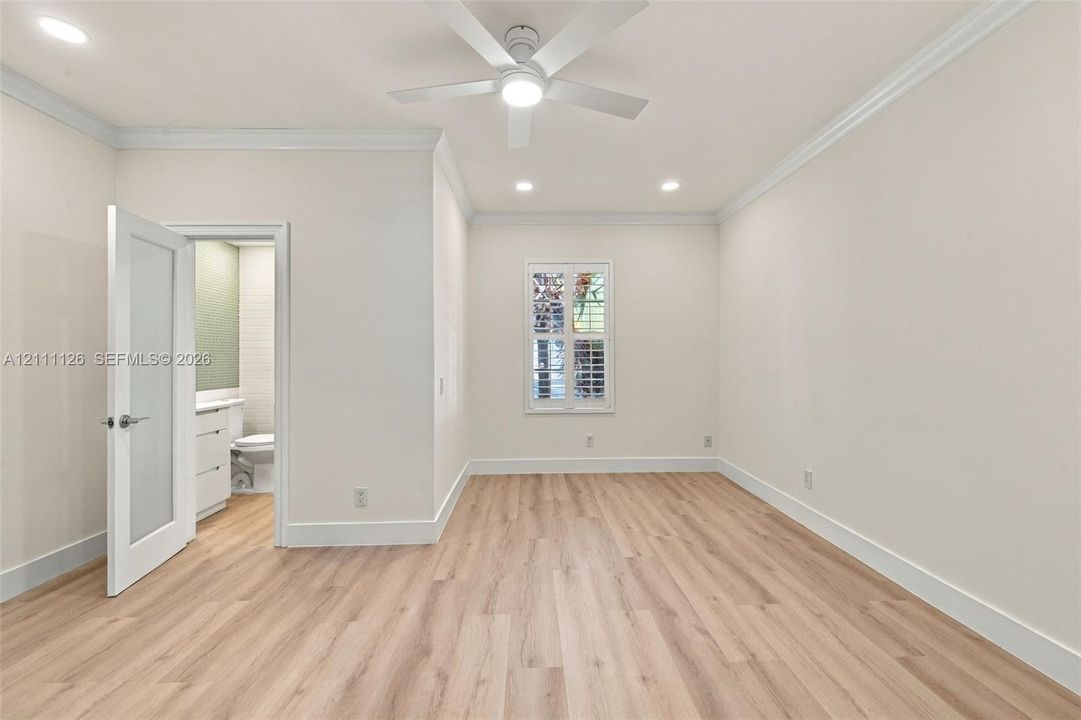 Interior space featuring wood-finish flooring, recessed lighting, crown molding, a modern ceiling fan with integrated lighting, and a single-panel interior door with glass insert