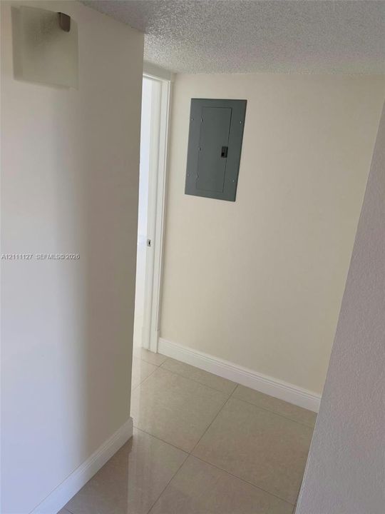 Neutral interior featuring large-format tile flooring, textured ceiling, and recessed electrical service panel