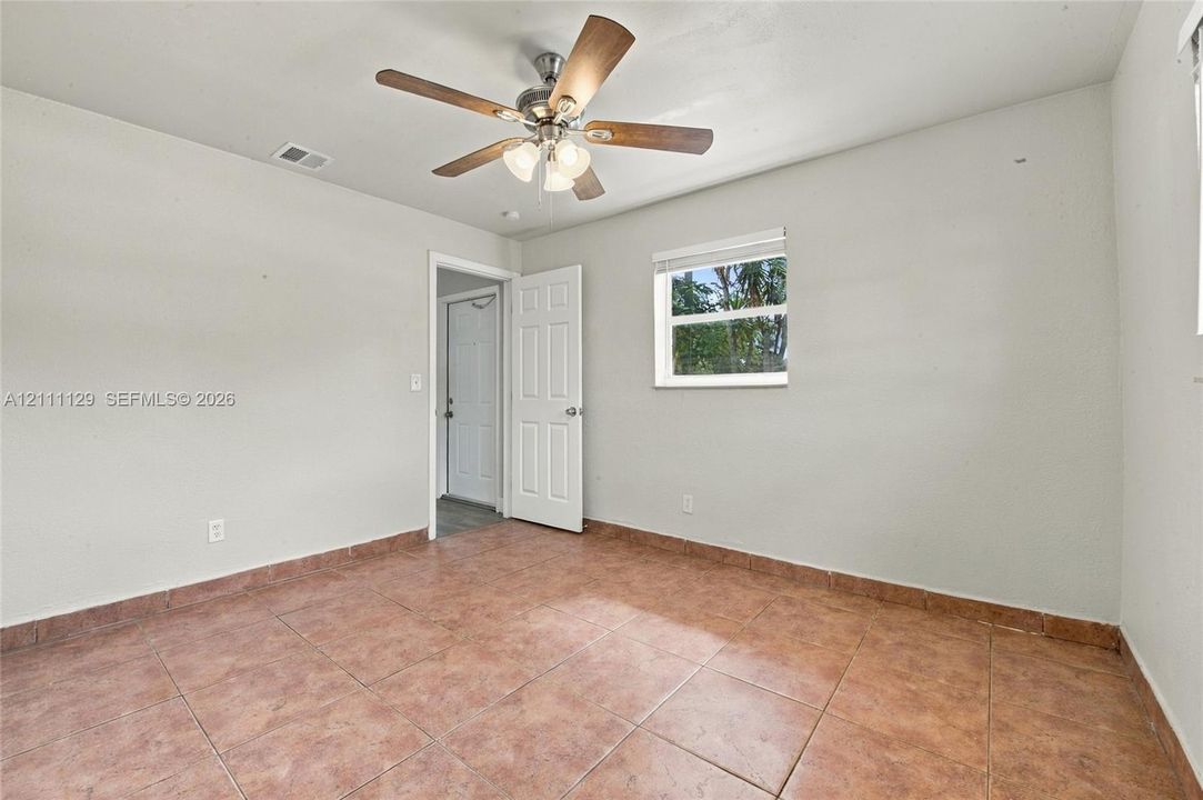 Interior room featuring oversized ceramic tile flooring, a multi-blade ceiling fan with integrated light fixture, a six-panel door, and a single-hung window