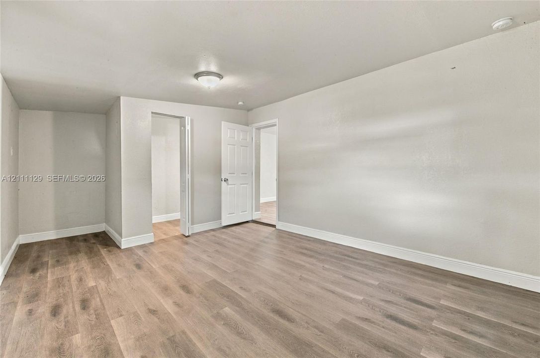 Interior space featuring wood-finish flooring, neutral wall paint, and a flush-mount ceiling light fixture