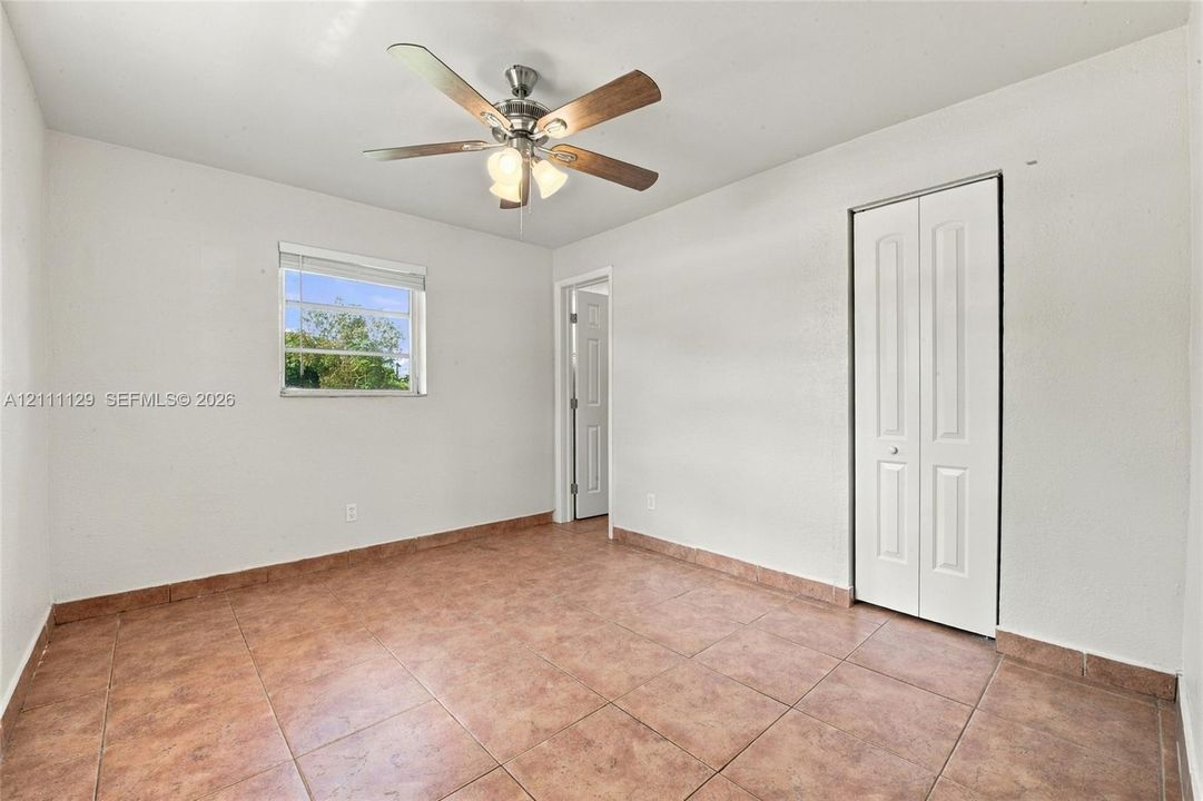Room featuring ceramic tile flooring, a multi-blade ceiling fan with integrated light fixture, a single-hung window, and a white bifold closet door