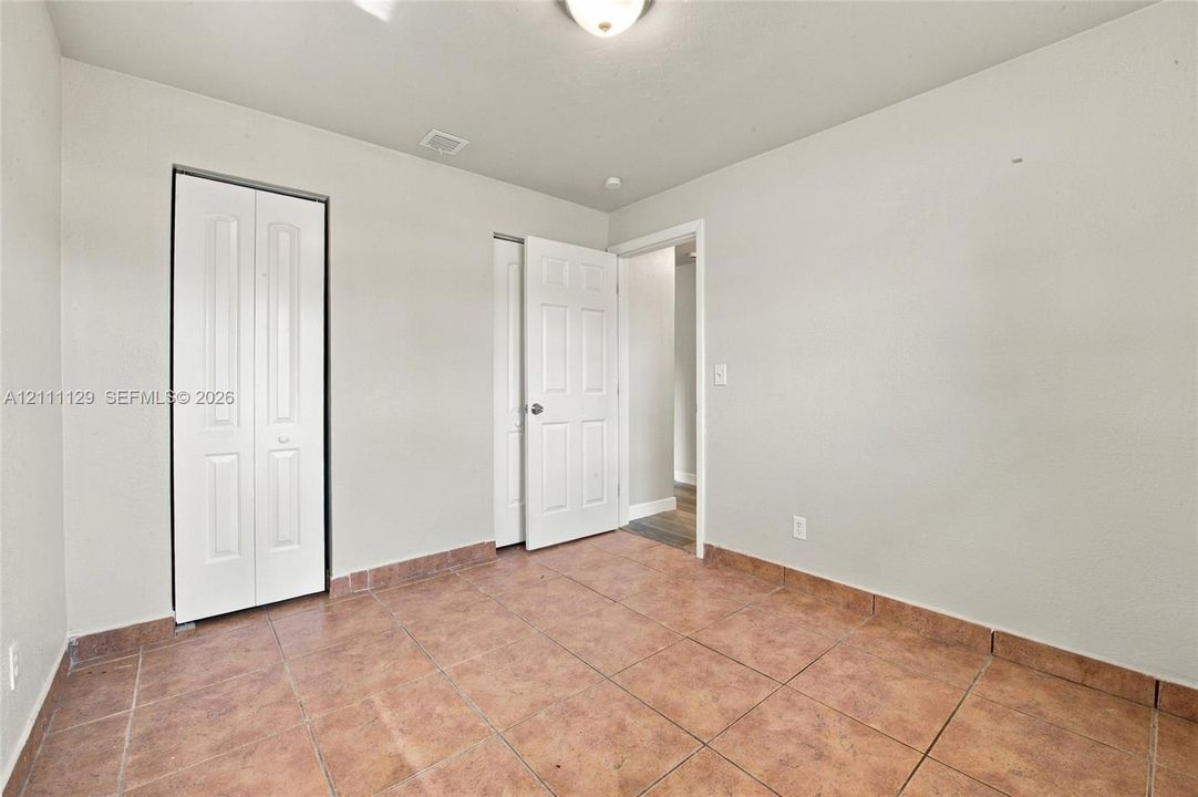 Interior space featuring neutral-toned walls, tile flooring, a six-panel swing door, and bi-fold closet doors