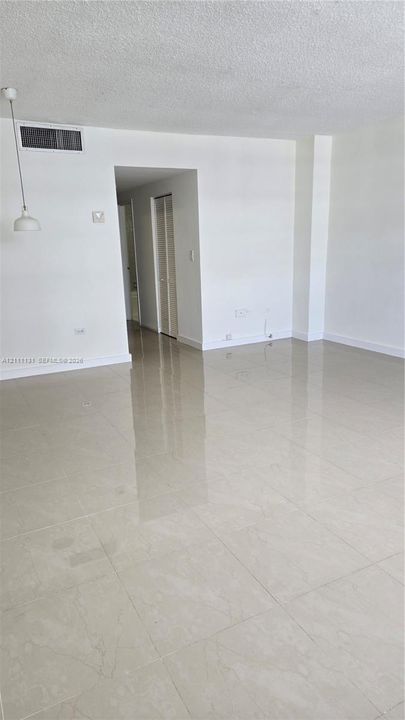 Polished neutral-toned floor tiling, white walls, and a single pendant light fixture