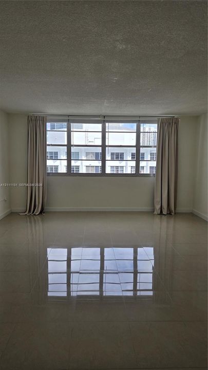 Large living area featuring polished tile flooring, neutral wall tones, and expansive multi-pane windows