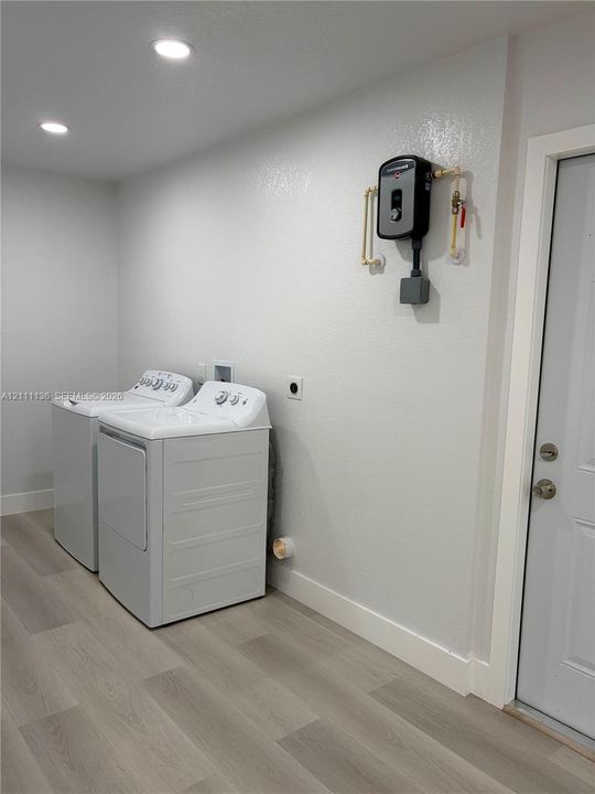 Laundry area featuring wood-finish flooring, recessed lighting, and a wall-mounted tankless water heater