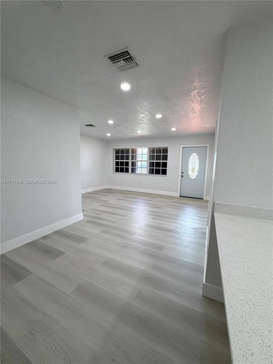 Interior space featuring wood-finish flooring, recessed lighting, neutral wall paint, multi-pane window, and an exterior door with an oval glass insert