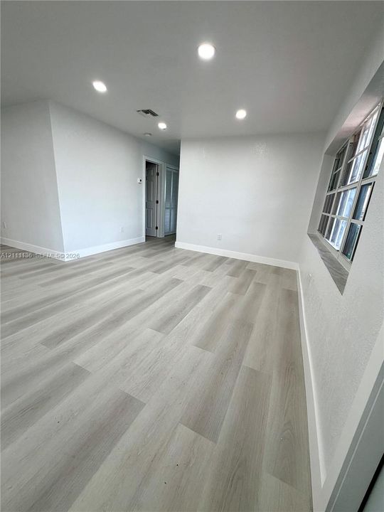 Interior space featuring wood-finish flooring, recessed lighting, neutral wall paint, multi-pane window, and an exterior door with an oval glass insert