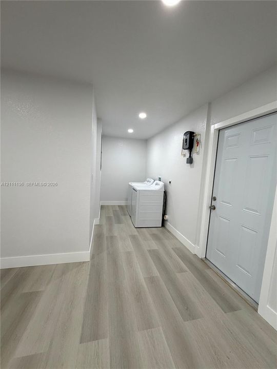 Laundry area featuring wood-finish flooring, recessed lighting, and a paneled entry door
