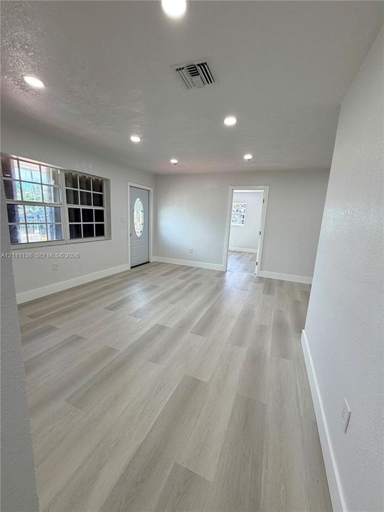 Light-toned wood-finish flooring, recessed lighting, multi-pane window, and exterior door with an oval glass insert