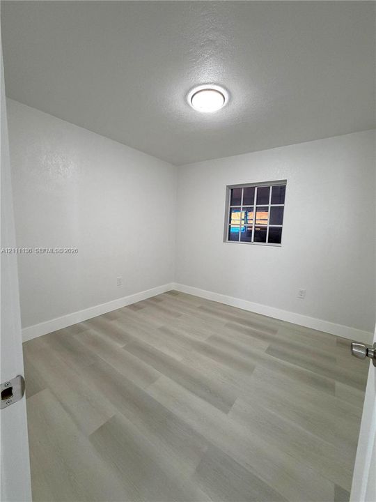 Interior room featuring wood-finish flooring, a multi-pane window, and a flush-mount ceiling light fixture
