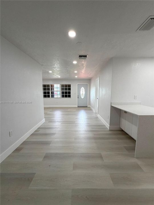 Interior featuring wood-finish flooring, recessed lighting, white cabinetry with stone-surface countertop, and an exterior door with decorative oval glass insert