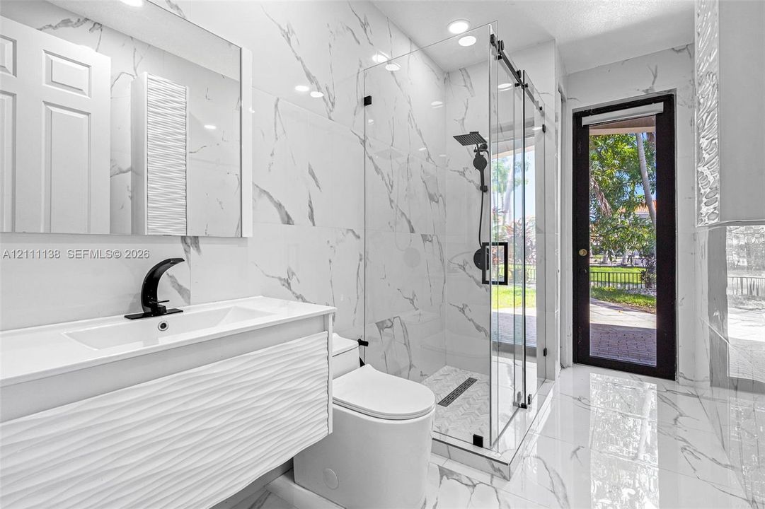 Bathroom featuring floor-to-ceiling porcelain tile, a glass-enclosed walk-in shower with matte black fixtures, a textured vanity cabinet, and a recessed medicine cabinet