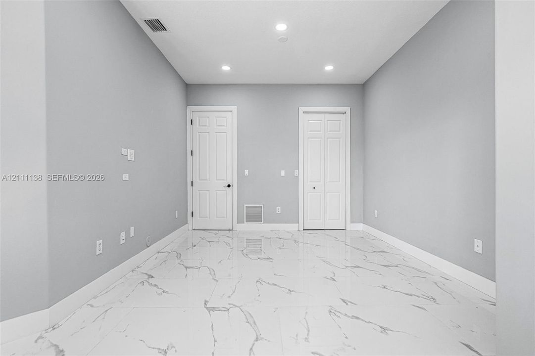 Neutral-toned interior featuring large-format stone-patterned tile flooring, recessed lighting, and white panel doors